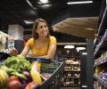 Woman with shopping cart buying food at supermarket.