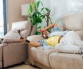 A photo of a handsome Hispanic man lying on a sofa and watching TV