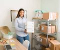 I have a growing business. Portrait of a beautiful female entrepreneur smiling and making eye contact while preparing packages ready to ship to customers