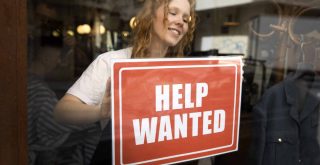 person-with-hiring-sign-by-window